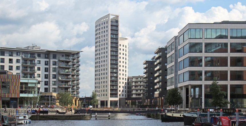 leeds, west yorkshire, united kingdom - 16 july 2019: a view of of leeds dock with clarence house surrounded by modern apartment developments and bars with moored houseboats and blue cloudy sky